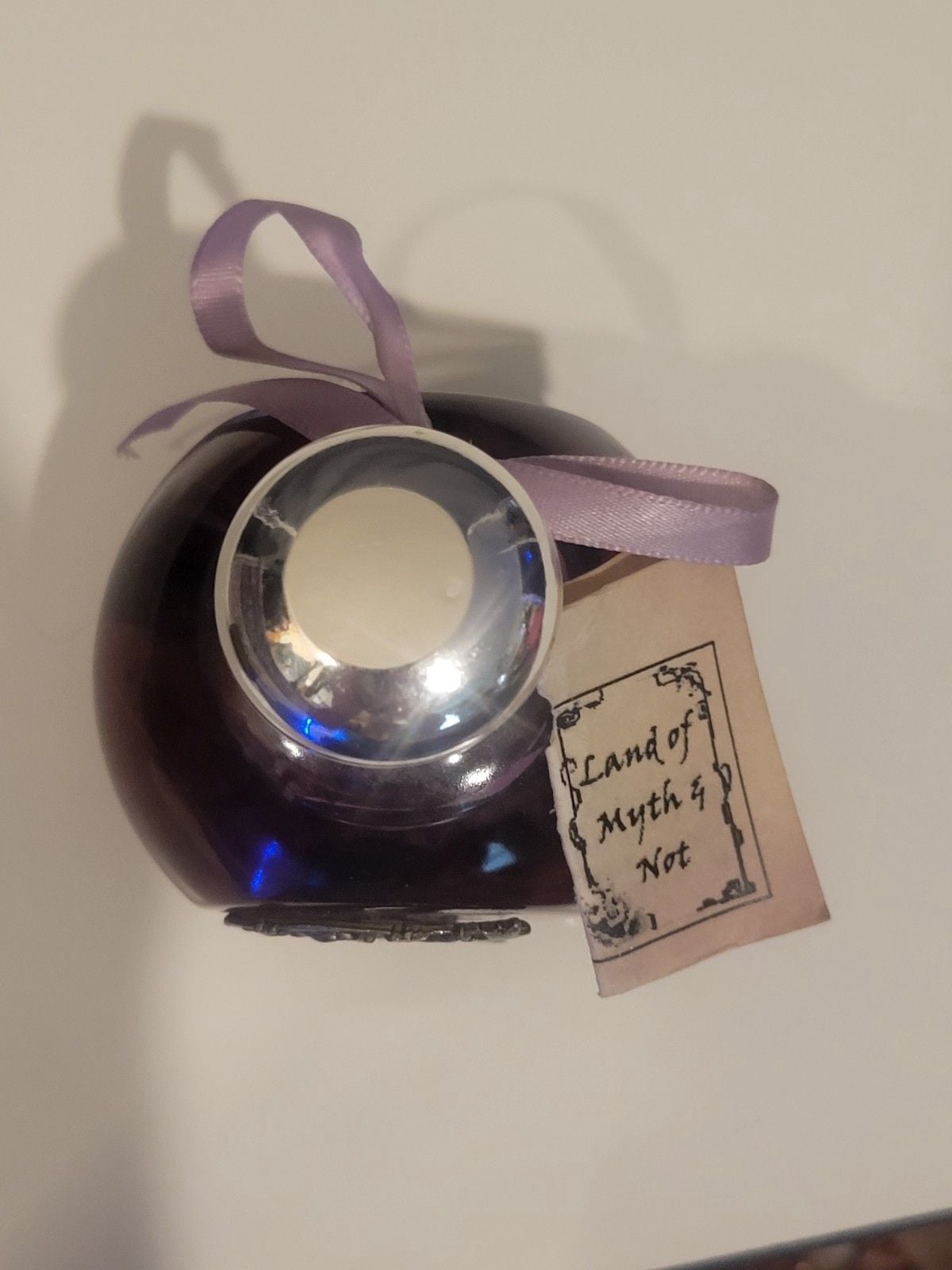Land of Myth & Not" purple oil candle featuring a pewter fairy on a moon design. 12