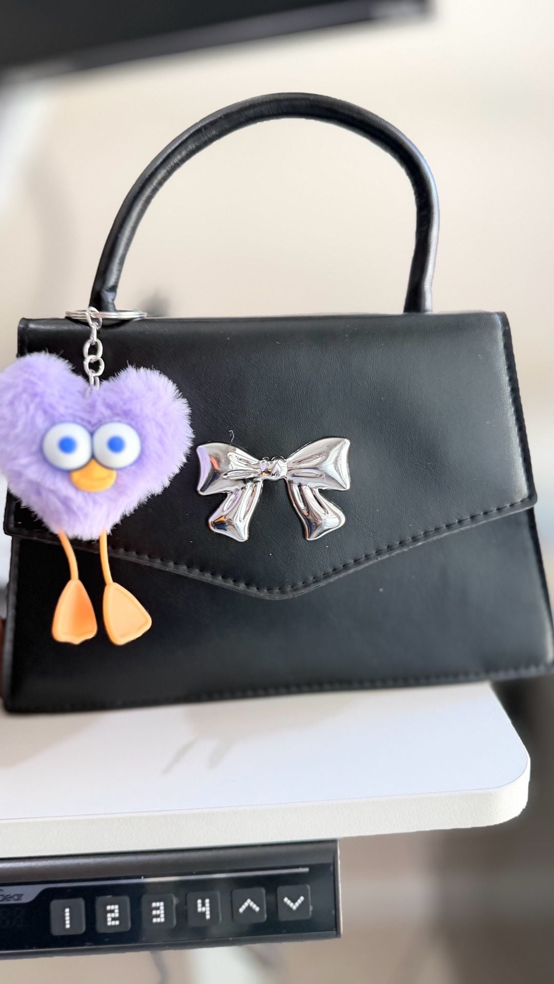 Minimalist Black Mini Square Handbag with Silver Bow Detail and Purple Heart Character Keychain 8