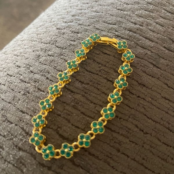 Gold tone tennis bracelet with four leaf clover shaped links. 