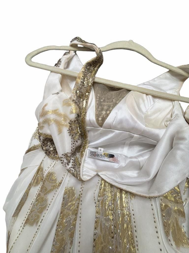 Sue Wong Gold And Cream Empire Waist Gown.
Hand-Applied Embellishments: Individual gowns often feature thousands of hand-stitched beads, sequins, and crystals combined with complex techniques like passementerie and soutache. 
Historical and Vintage Fusion 13